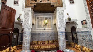 Um interior marroquino tradicional com um sofá estampado, uma mesa de centro e um candeeiro decorativo.