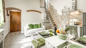 A modern kitchen with a stone backsplash, a wooden staircase, and a white dining area. - Dreamy Guelfa by Mmega (Florence)