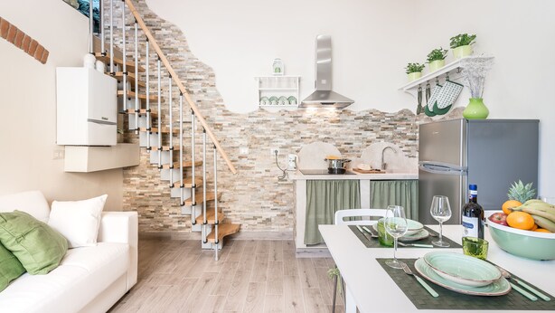 A modern kitchen with a stone backsplash, a built-in stove, and a refrigerator. - Dreamy Guelfa by Mmega (Florence)