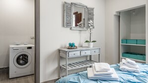 A laundry area with a washing machine, a mirror, a vanity with a plant, and a bed with towels. - Dreamy Guelfa by Mmega (Florence)