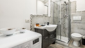 A modern bathroom with a glass-enclosed shower, a white sink, and a built-in washing machine. - Dreamy Guelfa by Mmega (Florence)