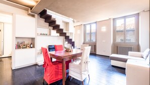Een moderne woonkamer met een eetgedeelte, een trap en een groot raam.