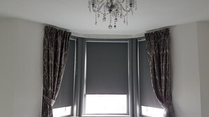 A room with a large window, dark curtains, and a chandelier. - The Dalby Rooms (Margate)