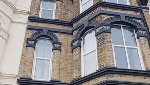 A corner building with a black door, large windows, and decorative brickwork. - The Dalby Rooms (Margate)