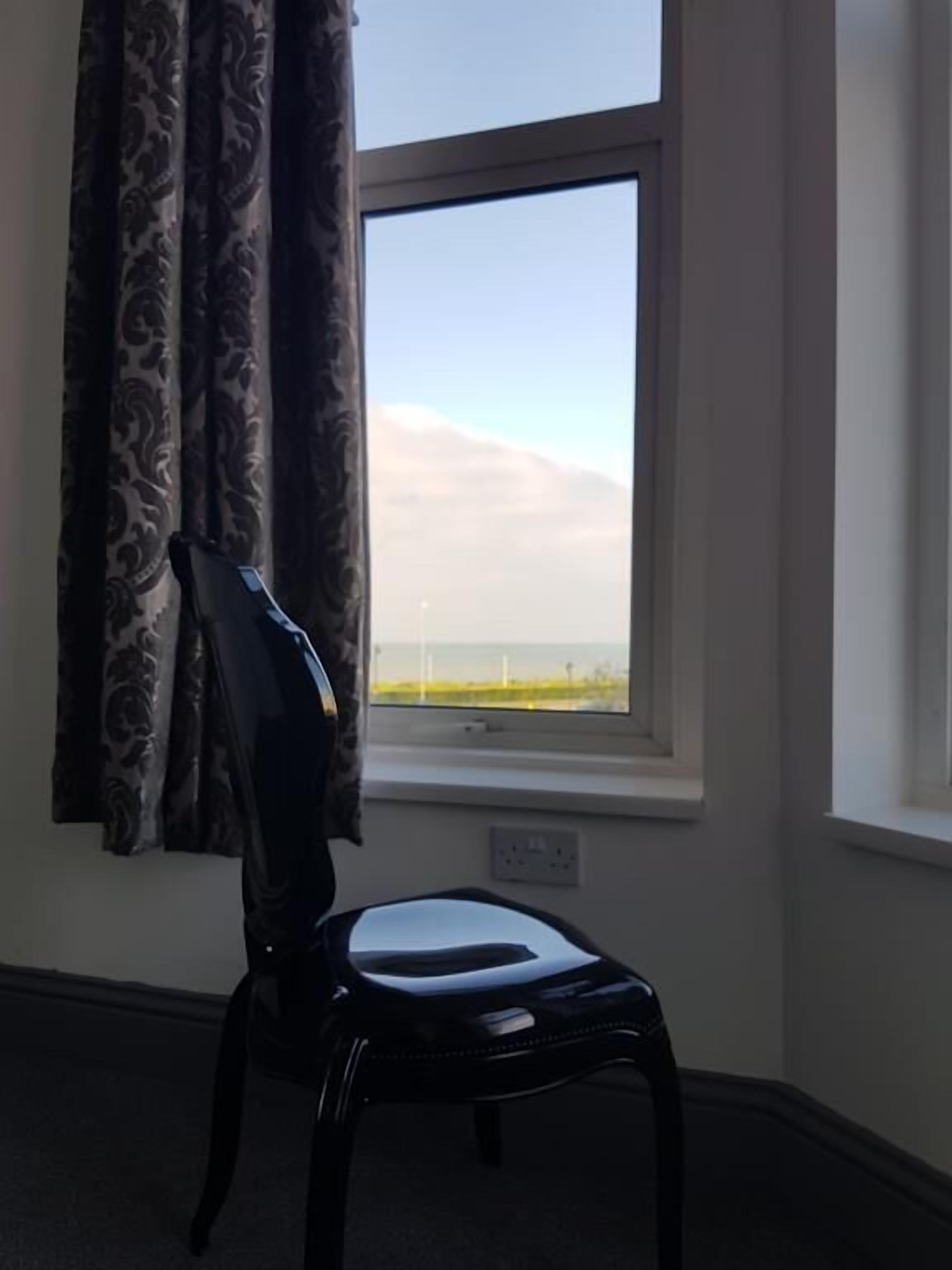 A room with a window, a chair, and a curtain.
