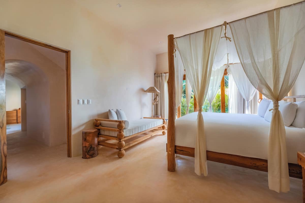 A bedroom with a wooden bed frame, a canopy bed, and a small bedside table.