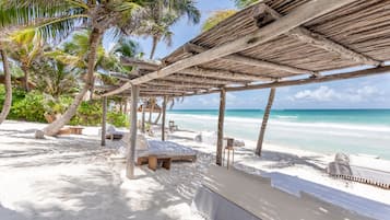 Een privéstrand, wit zand, ligstoelen aan het strand, parasols