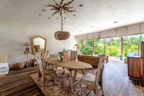 A dining area with a wooden table, chairs, and a hanging light fixture.