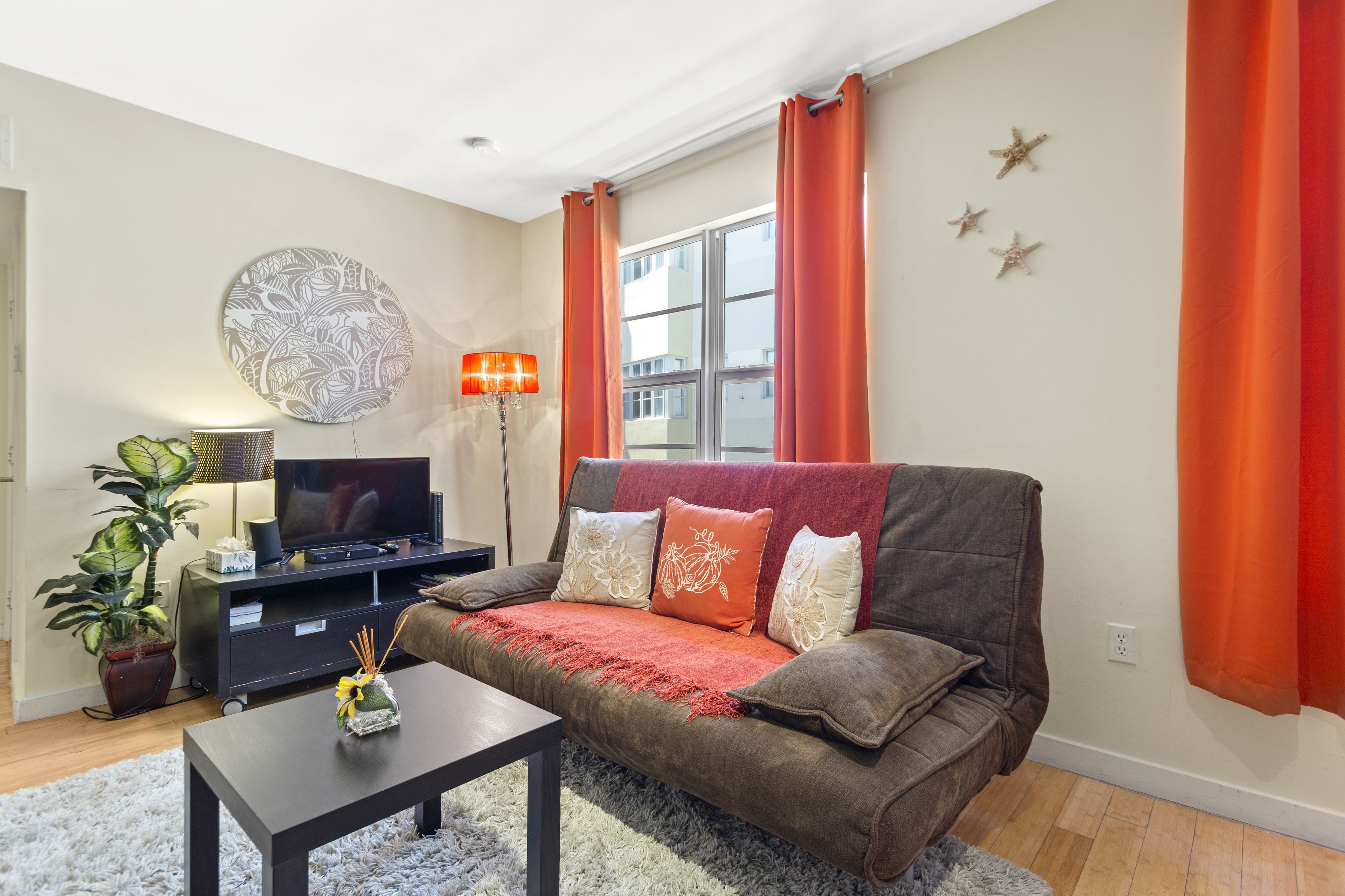 A living room with a sofa, TV, and decorative items.