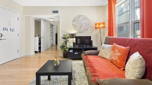 A modern living room with a sofa, coffee table, TV, and a decorative wall piece. - Apartment on the Beach (Miami Beach)