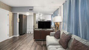 A modern living room with a flat-screen TV, a sofa with patterned cushions, and a dining area with a table and chairs. - Apartment on the Beach (Miami Beach)