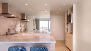 Una cocina moderna con una isla central, taburetes de bar, microondas y un ventanal que aporta luz natural.