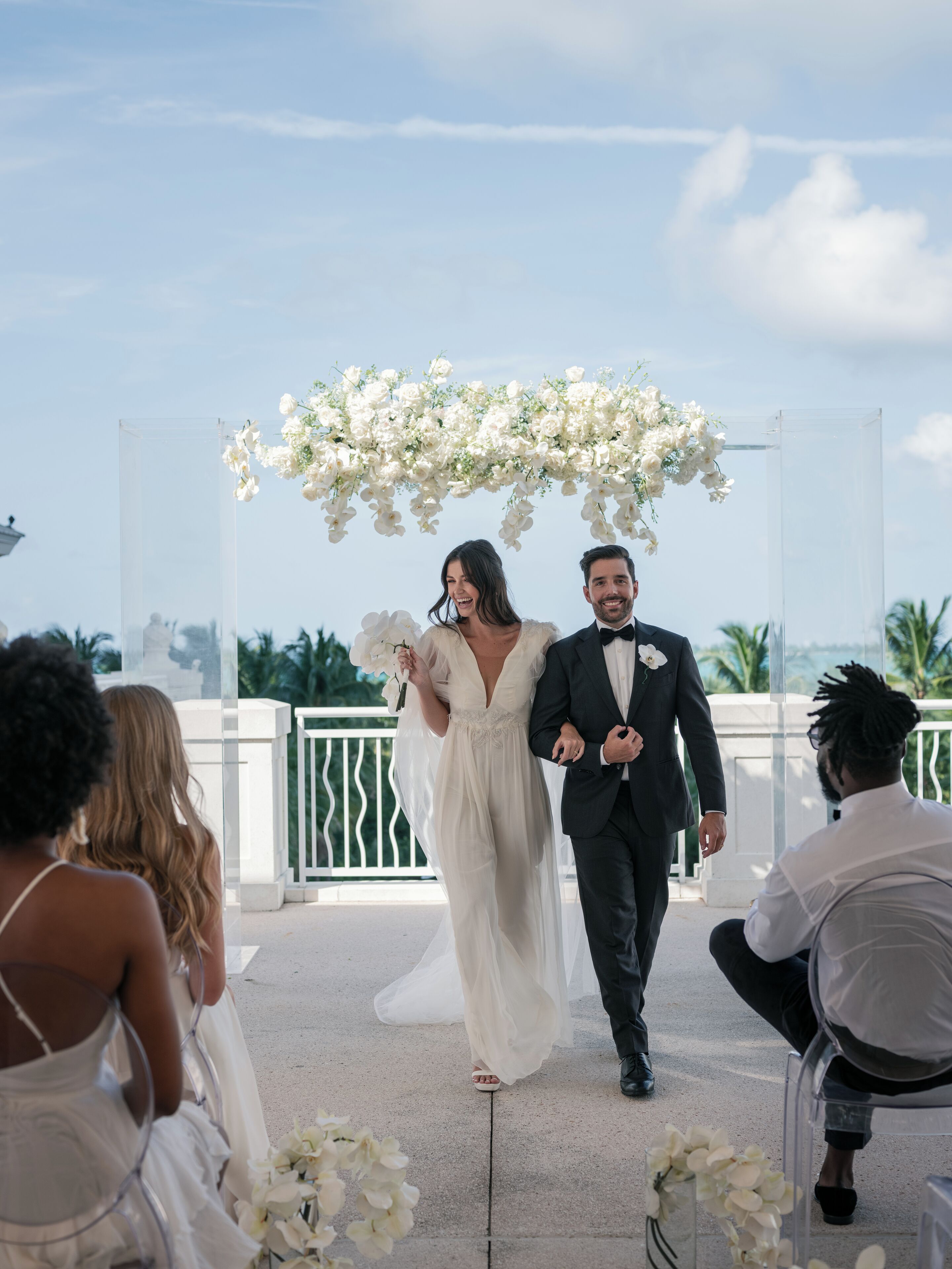 A wedding ceremony with a clear view of the aisle, floral decorations, and guests seated on either side.