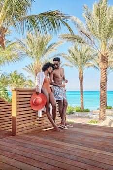 A high-rise hotel with multiple balconies overlooking a beach and pool area. at SLS Baha Mar