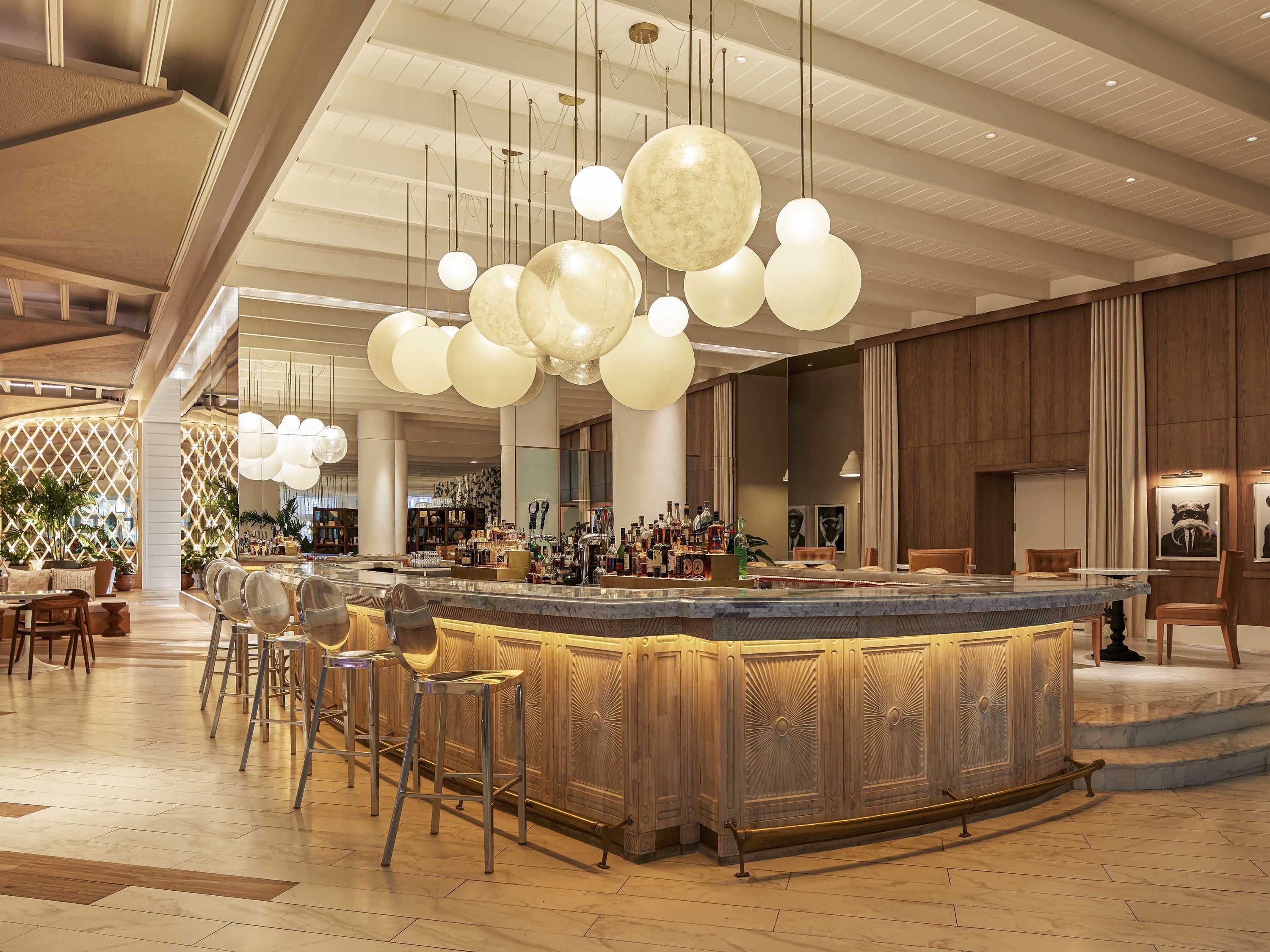 A spacious lobby with a bar area, high ceilings, and modern lighting fixtures.