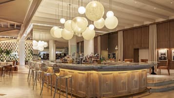 A spacious lobby with a bar area, high ceilings, and modern lighting fixtures.