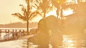 A couple in a swimming pool with a sunset in the background.