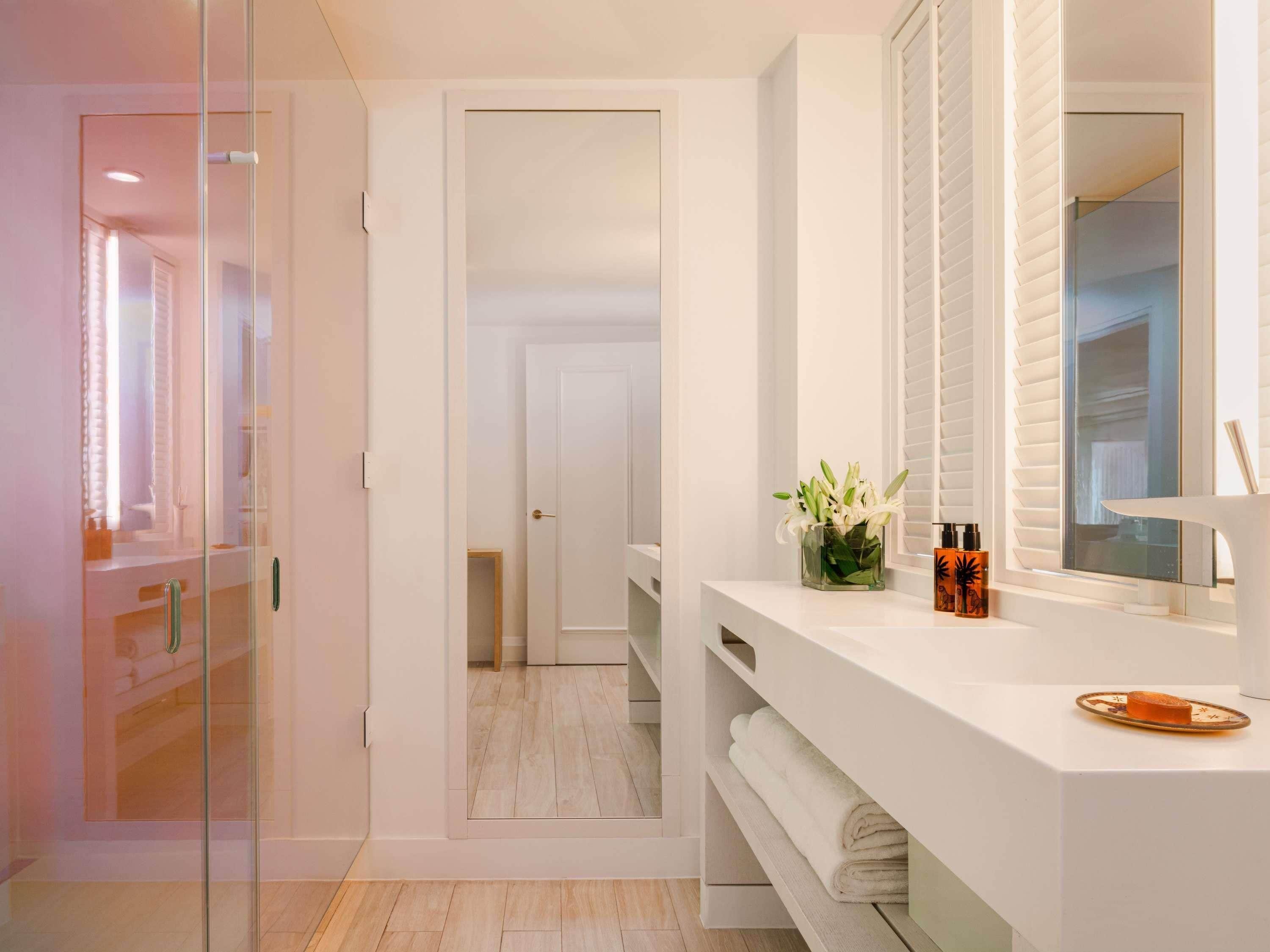 A modern bathroom with a glass shower enclosure, a white vanity with a mirror, and a small plant on the counter.