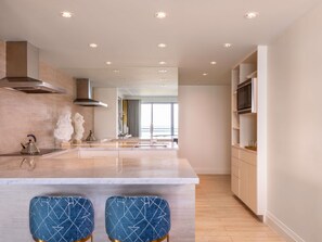 A modern kitchen with a central island, bar stools, a microwave, and a large window providing natural light.