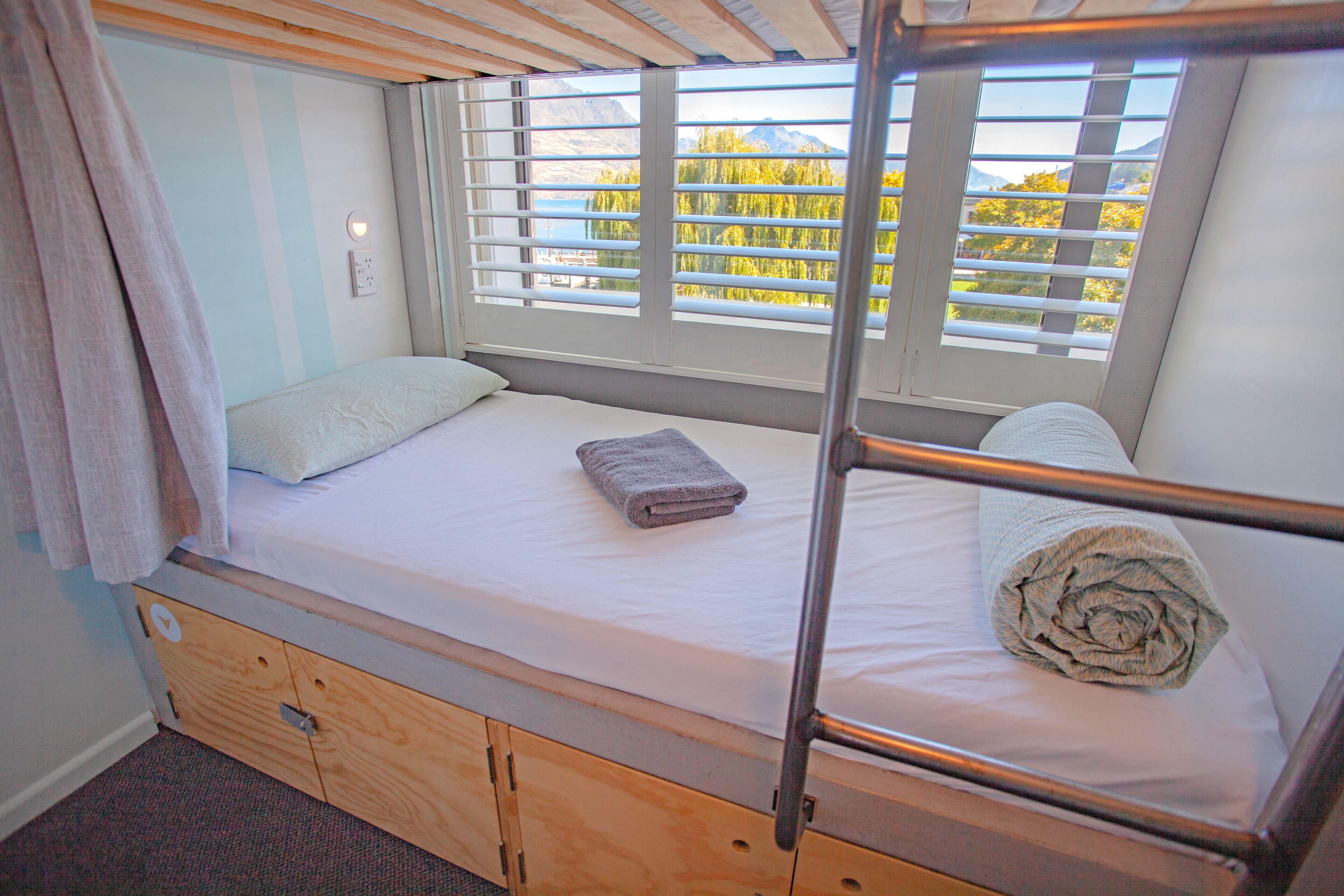 Cama litera con vistas a árboles y montañas a través de las persianas.