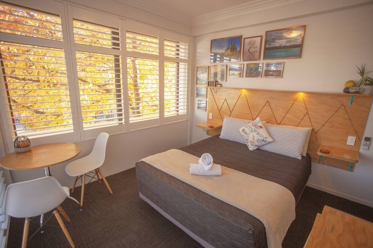 A bedroom with a large bed, a bedside table, a chair, and a small table.
