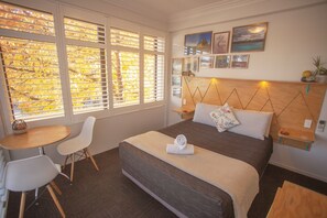 Une chambre avec un grand lit, une table de chevet, une chaise et une petite table.