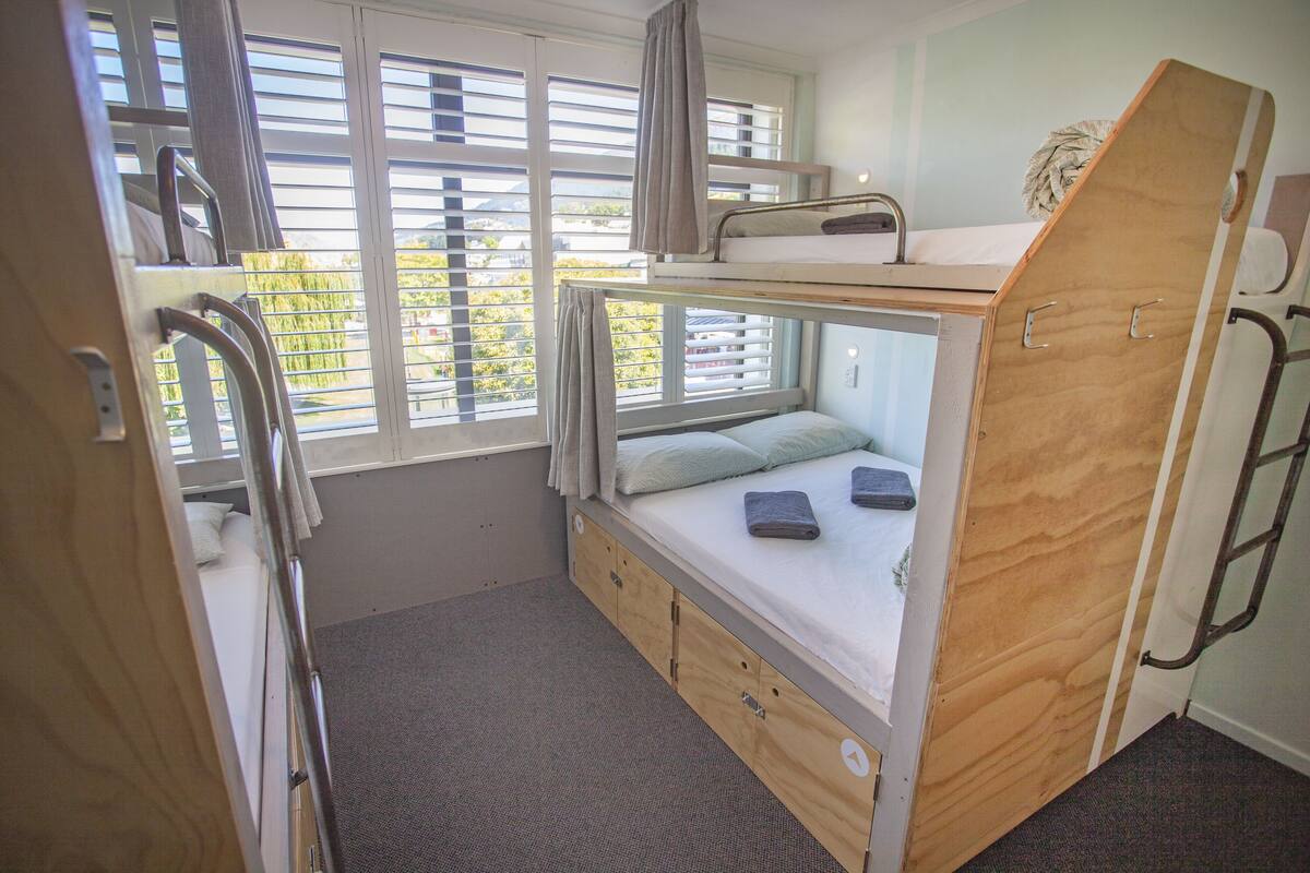 A bunk bed room with a window, a desk, and a chair.