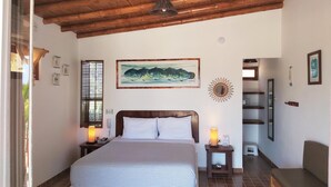 A bedroom with a large bed, wooden ceiling, a painting, a mirror, and a small table with a lamp. - Punta del Norte Bungalows (Canoas de Punta Sal)