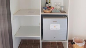 A hotel room with a white wardrobe, a small refrigerator with a note, and a tiled floor. - Punta del Norte Bungalows (Canoas de Punta Sal)
