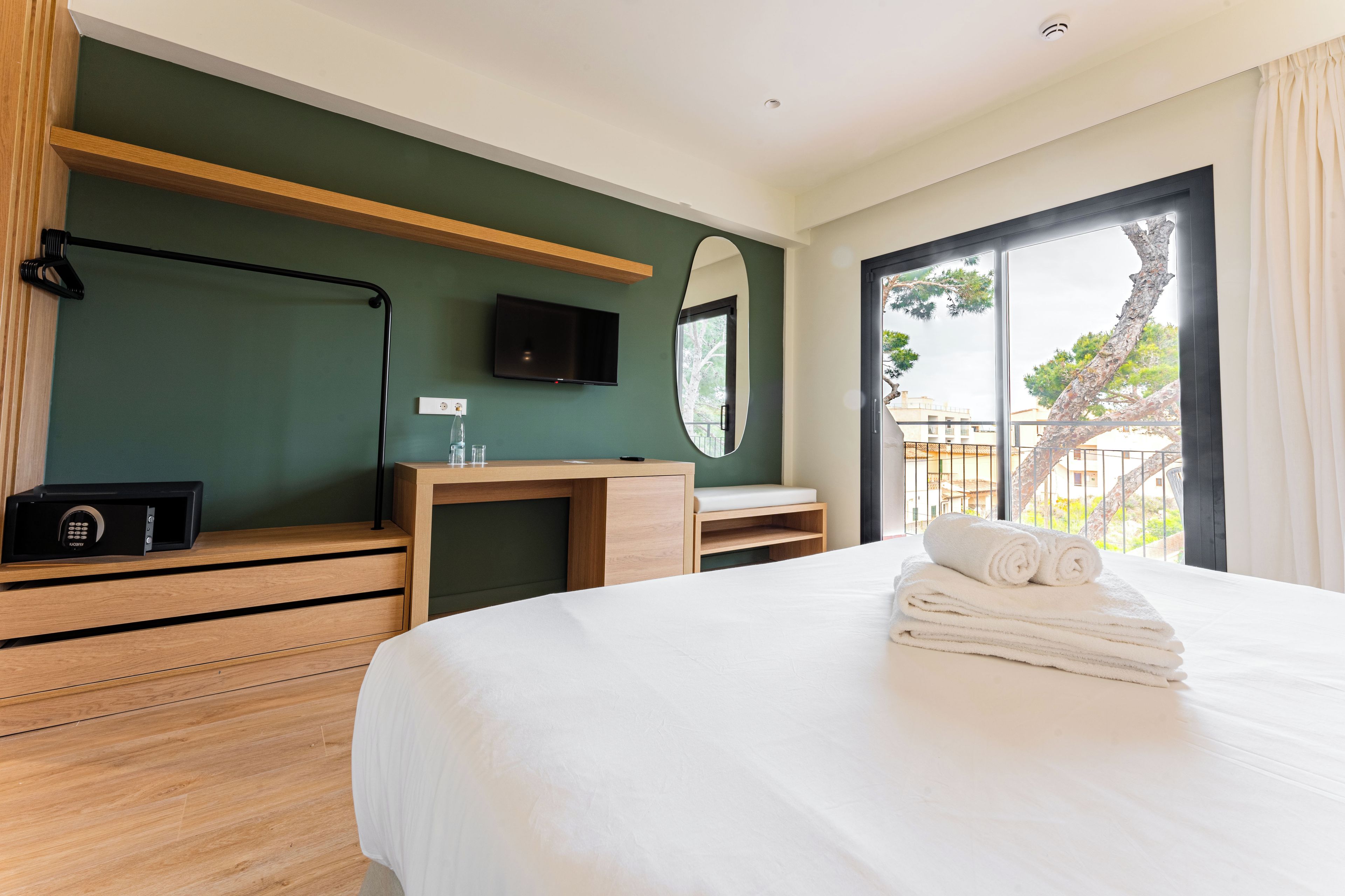Une chambre d’hôtel avec un lit, un bureau en bois, une télévision et une vue sur l’extérieur.