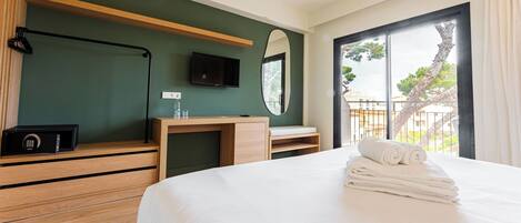 Une chambre d’hôtel avec un lit, un bureau en bois, une télévision et une vue sur l’extérieur.