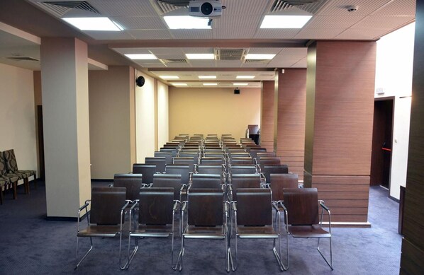A conference room with rows of chairs, a projector, and a clock on the wall. - Hotel Presidium Palace (Lovech)