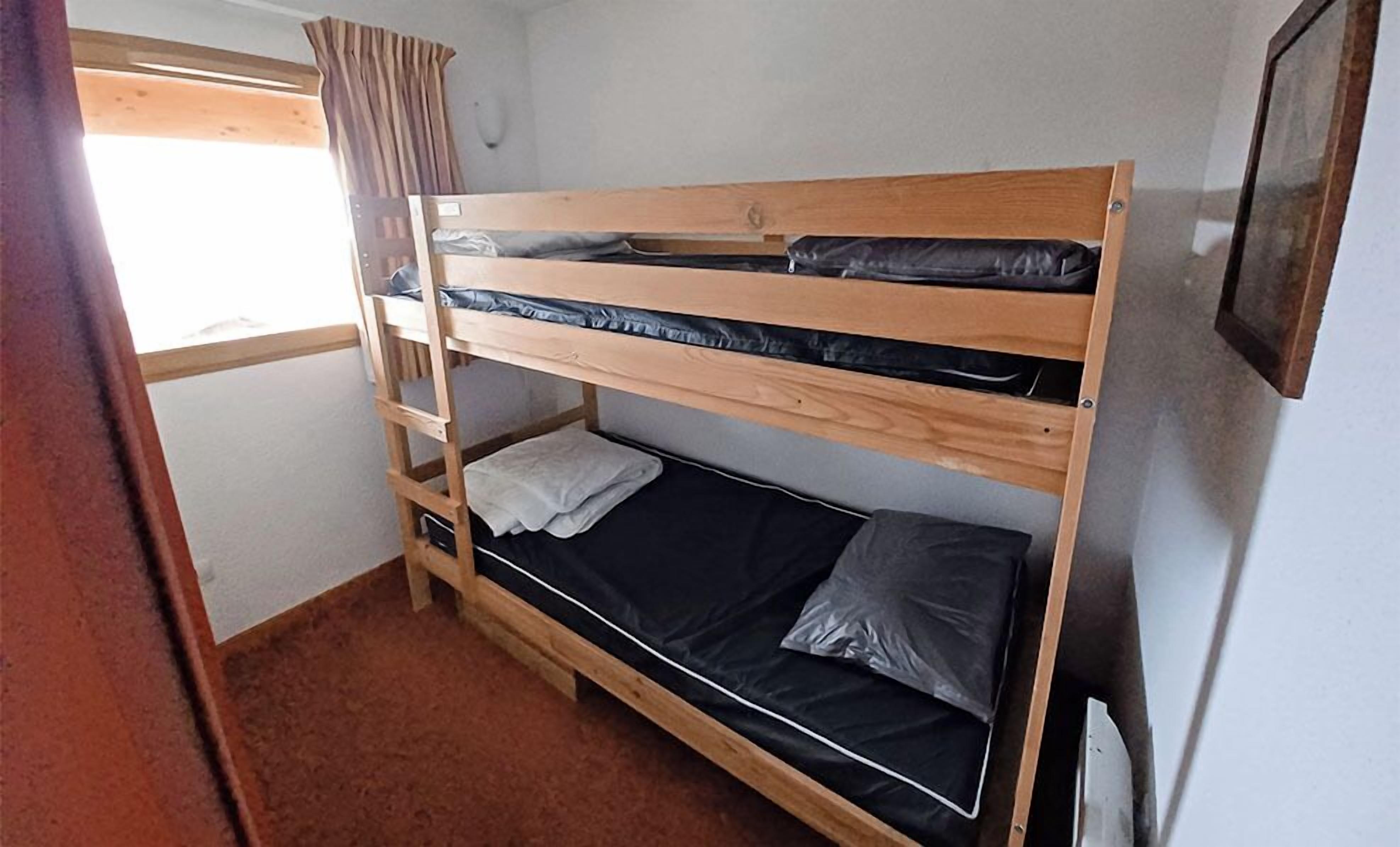 A bunk bed room with a window and a radiator.