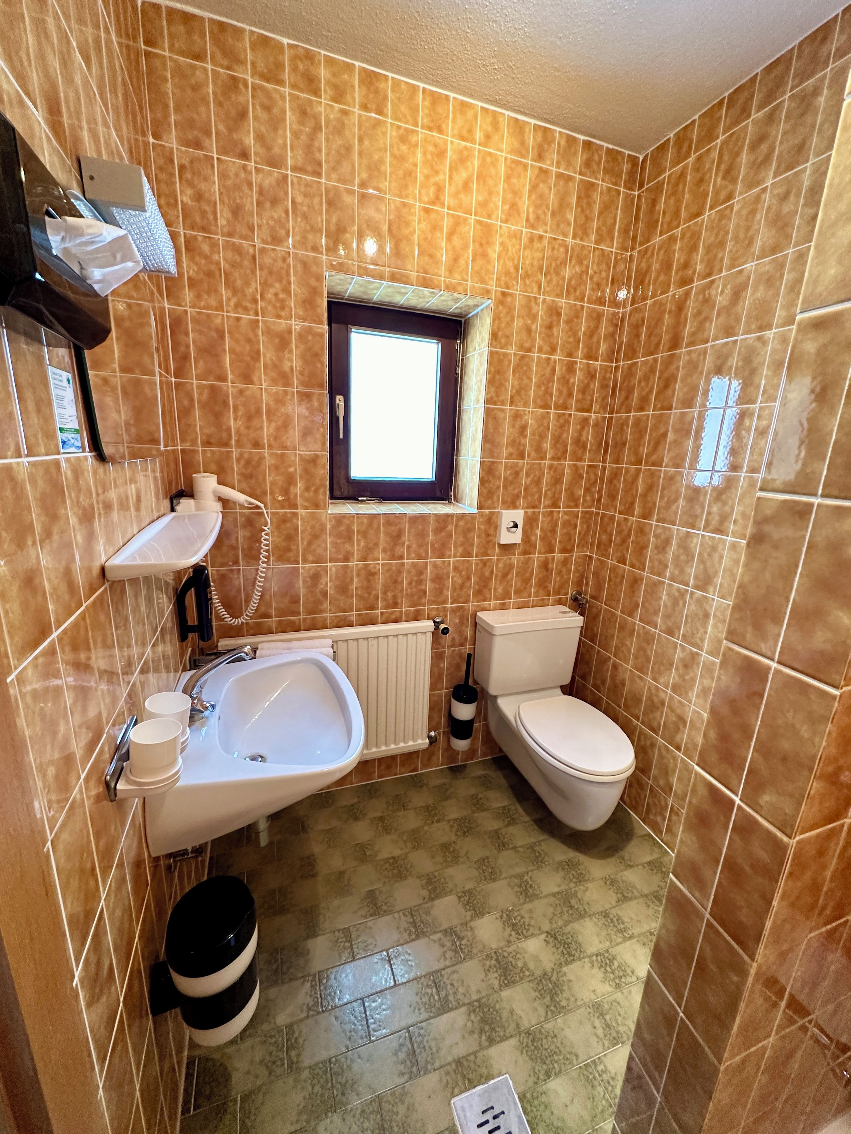 A bathroom with a sink, toilet, and a small window.