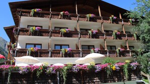 Un edifici de diverses plantes amb balcons decorats amb flors i paraigües de sol.