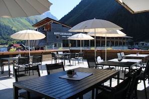 Un espace extérieur aménagé avec des tables, des chaises, des parasols et une vue sur une montagne.