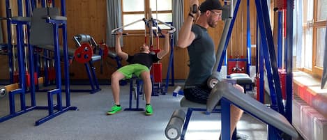 A gym with various exercise equipment, including a pull-up bar and weight machines.