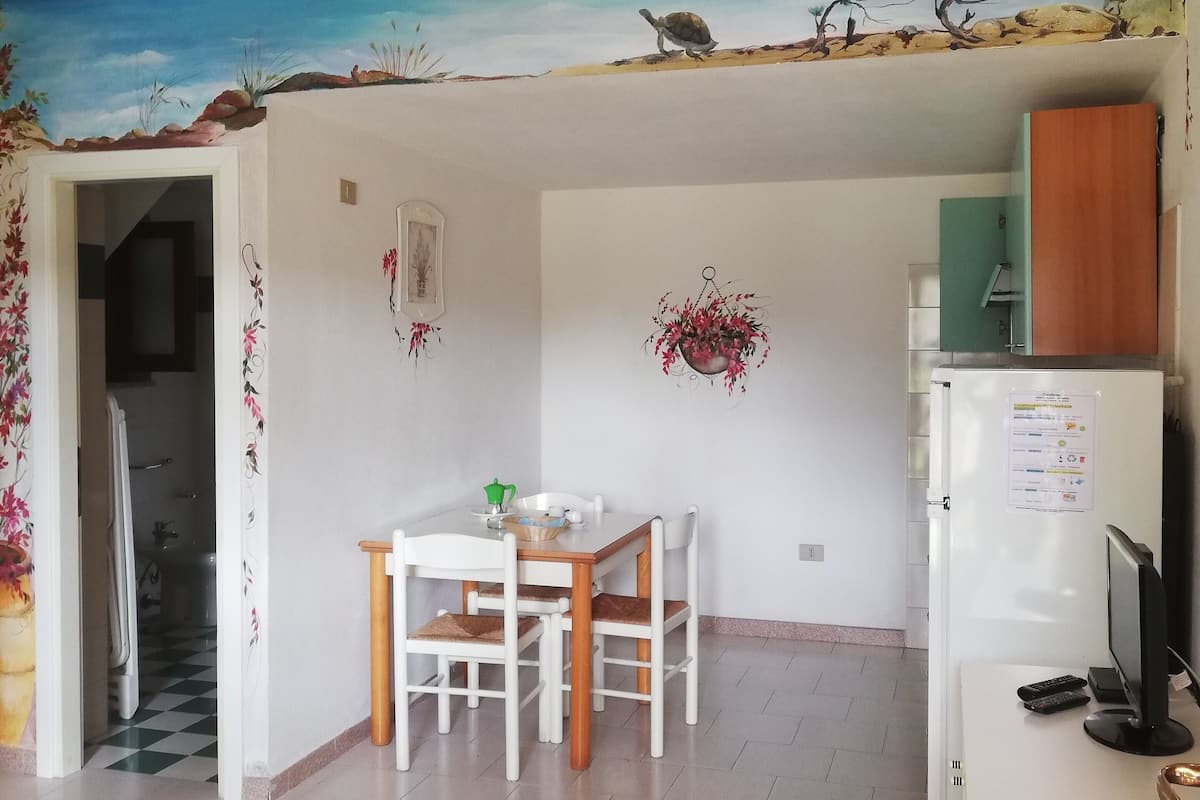 A dining area with a table and chairs, a refrigerator, and a wall-mounted TV.