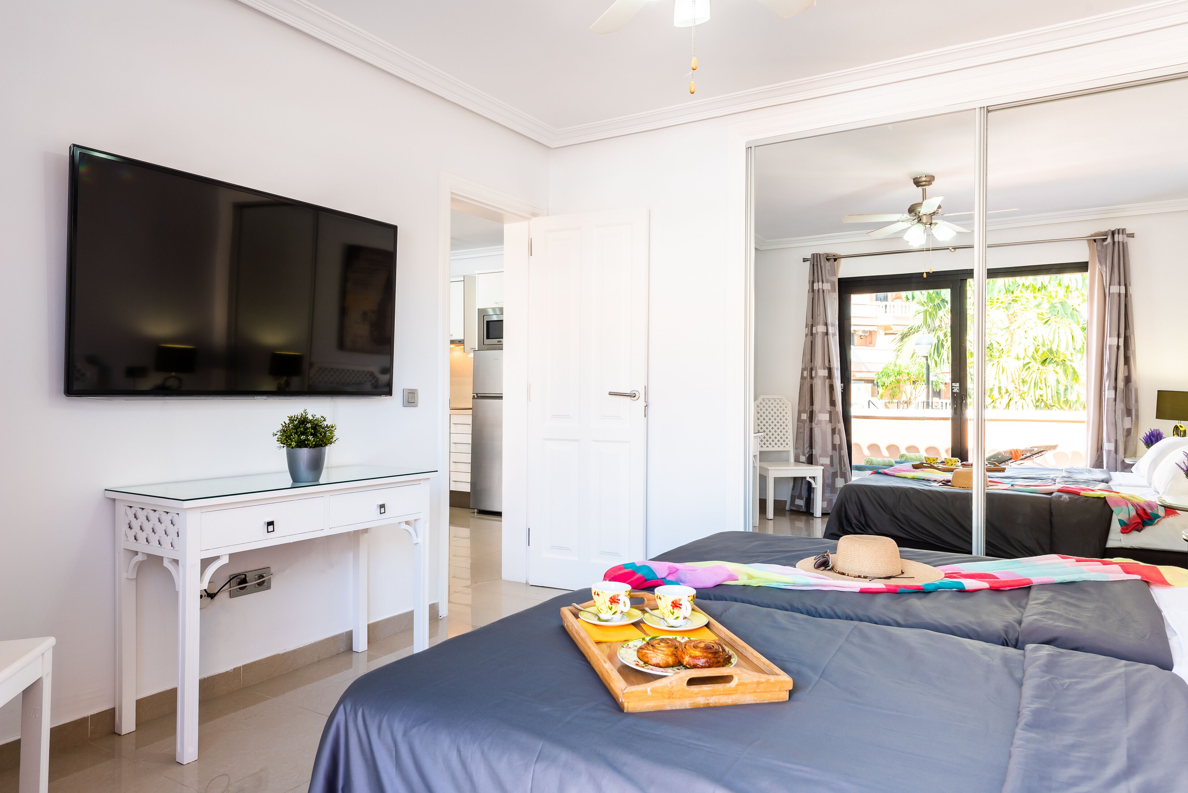 Ein Hotelzimmer mit Bett, Fernseher, Schreibtisch und einem Balkon mit Blick ins Freie.