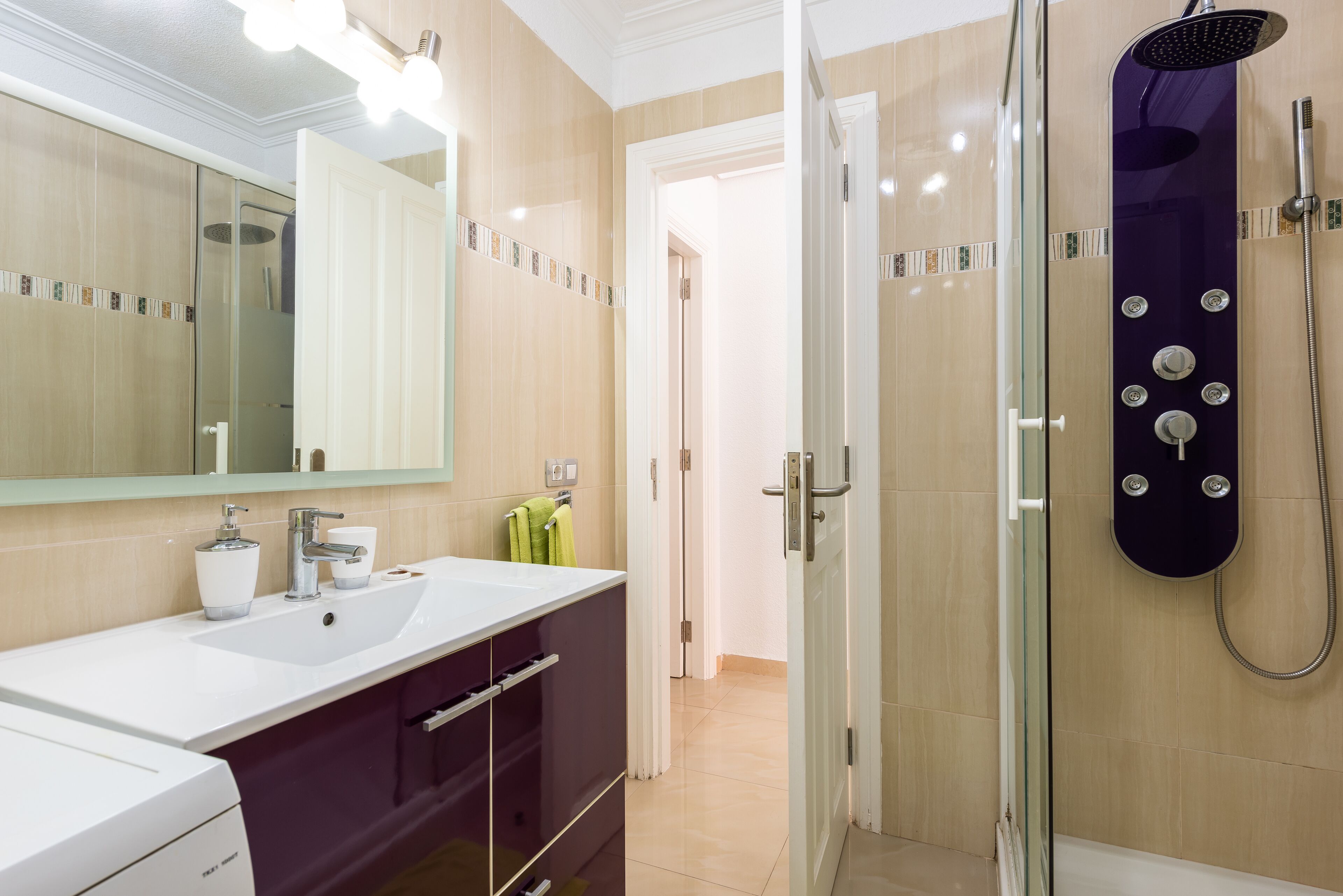 Un baño moderno con ducha de vidrio, un lavamanos blanco y un tocador con espejo.