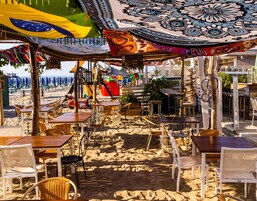 Un café junto a la playa con terraza, zona de juegos y vistas al mar.