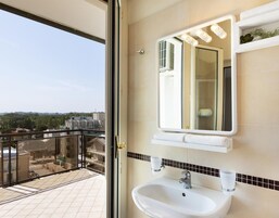 A bathroom with a large mirror, a sink, and a towel rack.