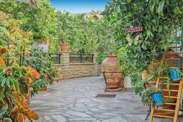 A stone-paved courtyard with potted plants and a welcome sign. - Golden Sun Kokkari (Samos)