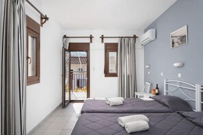 A bedroom with two beds, a balcony, and a view of the outside. - Golden Sun Kokkari (Samos)