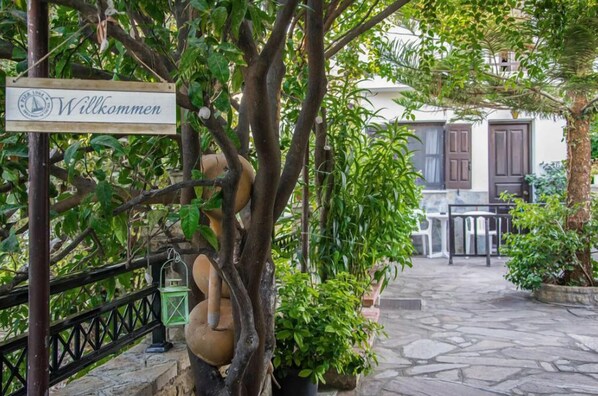 A welcoming sign with a tree and outdoor seating area. - Golden Sun Kokkari (Samos)