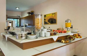 A buffet setup with various food items and a juice dispenser. - Golden Sun Kokkari (Samos)