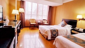 Ein Hotelzimmer mit zwei Betten, einem Schreibtisch, einem Stuhl und einem Fernseher.