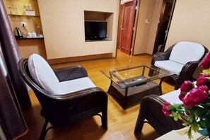 A living room with two black leather sofas, a glass coffee table, and a wooden floor. - Hedong Hotel (Shenzhen)