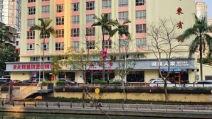 Ein mehrstöckiges Hotel mit auffälliger Beschilderung in einer Fremdsprache, umgeben von Palmen und parkenden Autos.
