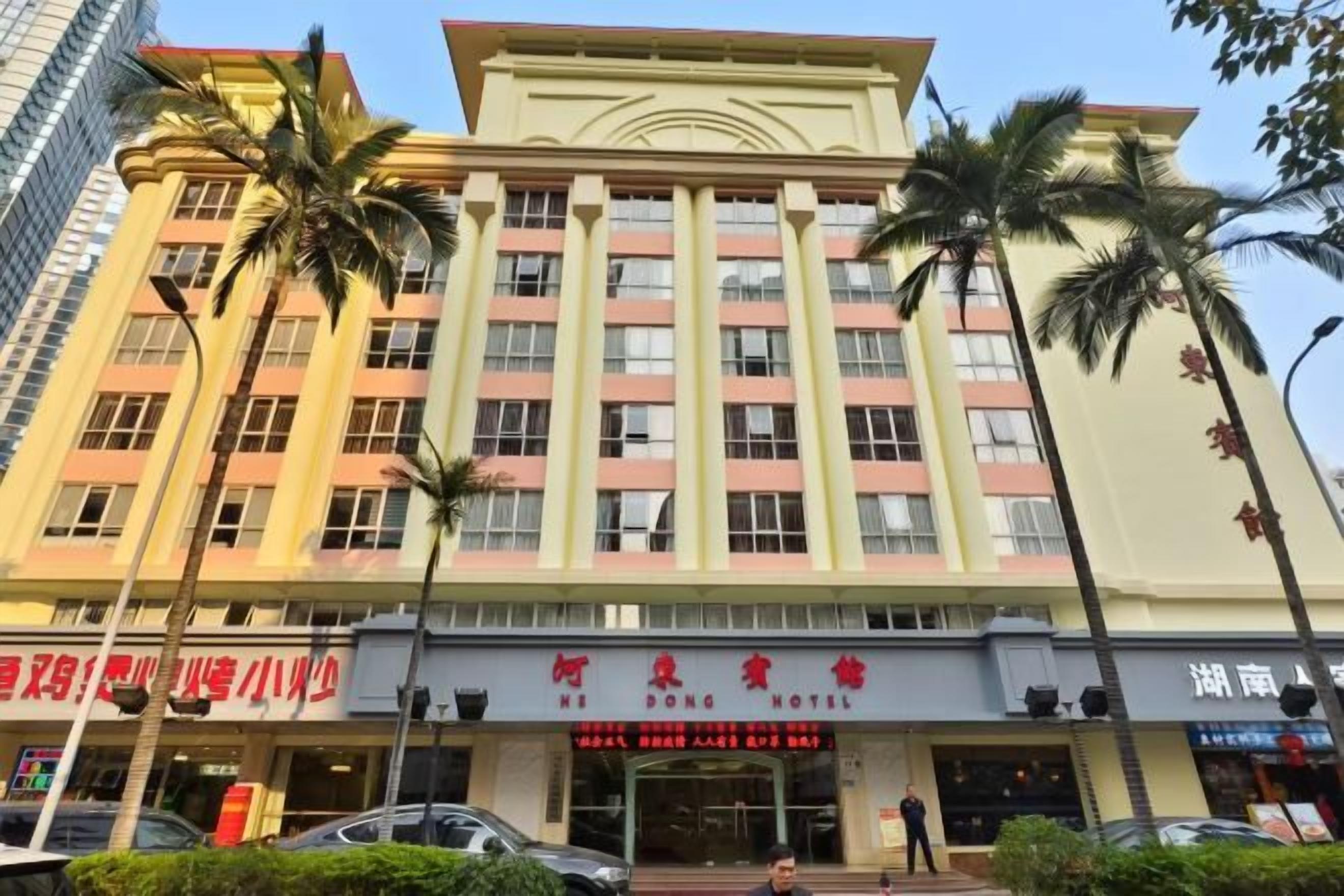 A hotel with multiple floors, a prominent entrance, and palm trees in front.